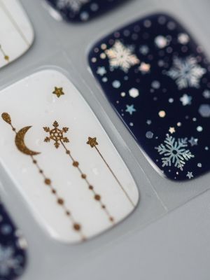 Nahaufnahme der Winterhimmel UV Gel Wraps – feine Gold- und Schneeflockenmotive auf Blau und Weiß für einen festlichen Look.