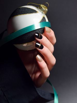 Hand mit schwarzem Nageldesign und goldener Linie – eleganter Look der Die Nageltante Nailpolish Wraps.