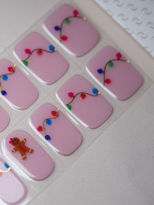 Gingerbread Lights UV Gel Wraps – rosa Nageldesign mit bunten Lichterketten und kleinen Lebkuchenmännchen.