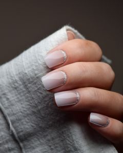 Hand mit UV Gel Wraps Babyboomer Nude Glitter – Nude-Ombré Nägel mit silbernem Glitzer-Rand.