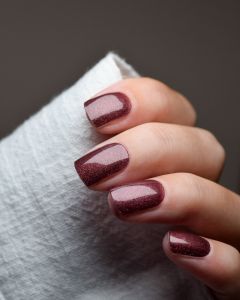 Hand mit UV Gel Wraps Rusty Spark – rostrote Nägel mit feinem Schimmer.